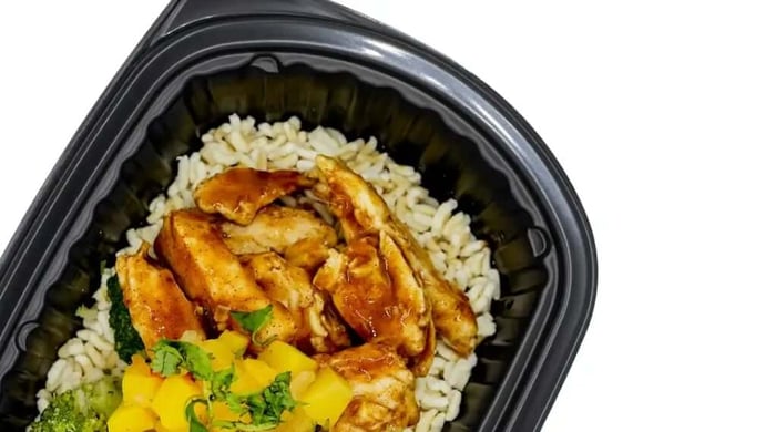 High-protein meal featuring grilled chicken with brown rice, broccoli, and mango salsa in a portioned black container