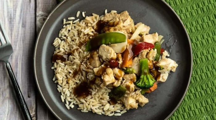 Low-calorie meal showing lean chicken stir fry with vegetables over brown rice, served on a simple plate