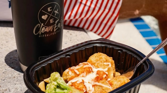 portion-controlled meals in a black container with breaded entrée, broccoli, pasta, and a branded Clean Eatz tumbler