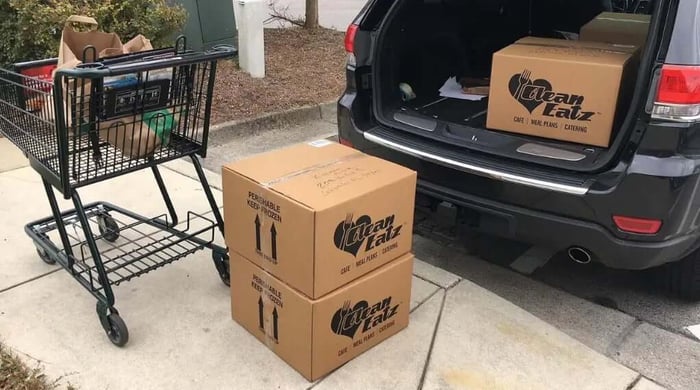 Premade meal delivery displayed as Clean Eatz Kitchen boxes loaded into a vehicle trunk for convenient home delivery