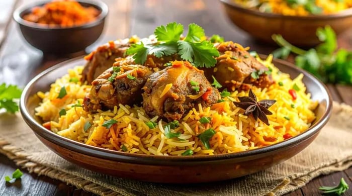 Aromatic sticky asian chicken stir-fry with saffron-tinted basmati rice garnished with fresh cilantro and whole star anise on a wooden table.