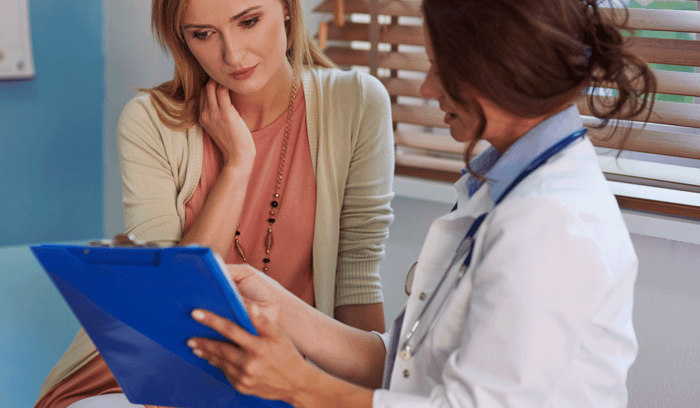 Doctor discussing medical results on clipboard with female patient