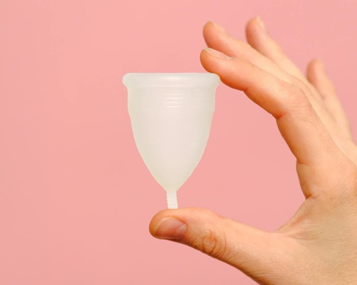 a white diva cup against a pink background