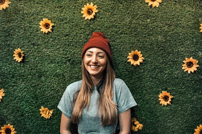 Woman smiling in front of green floral wall