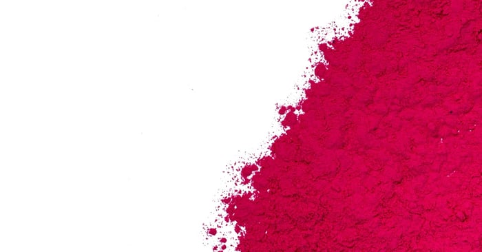 A spread of pink-red acrylic nail powder that gradually disperses as the image transitions to a white background.