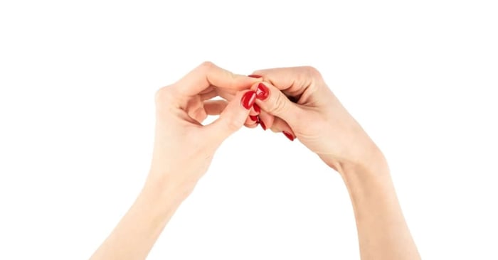 A woman's hands and arms are against a plain, white background. The nails are painted bright red.