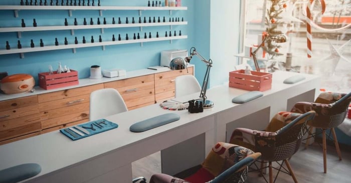Manicure tools rest on a salon desk as cozy chairs line up for clients in a clean, modern workspace.