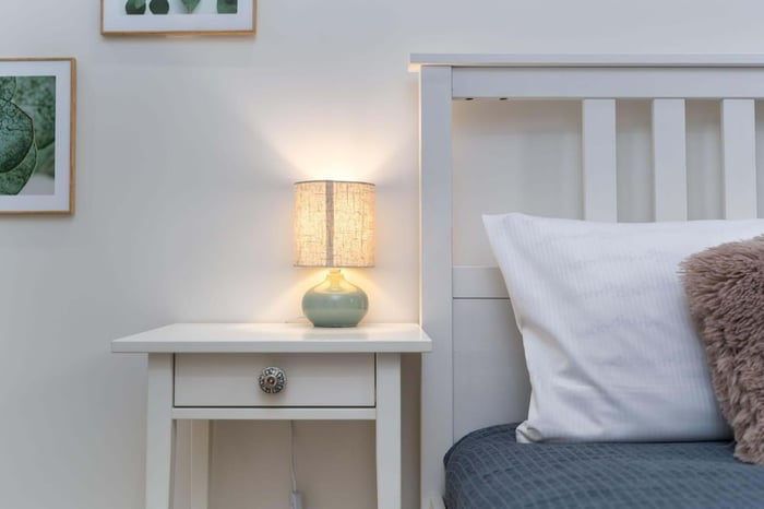 Cozy bedroom with bedside table, lamp, pillows, and bed