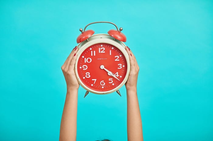 Hands holding clock against blue background