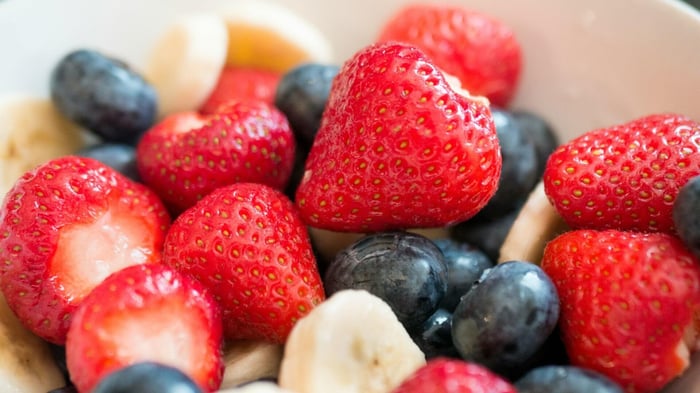 a close up of banana slices, strawberries and blueberries