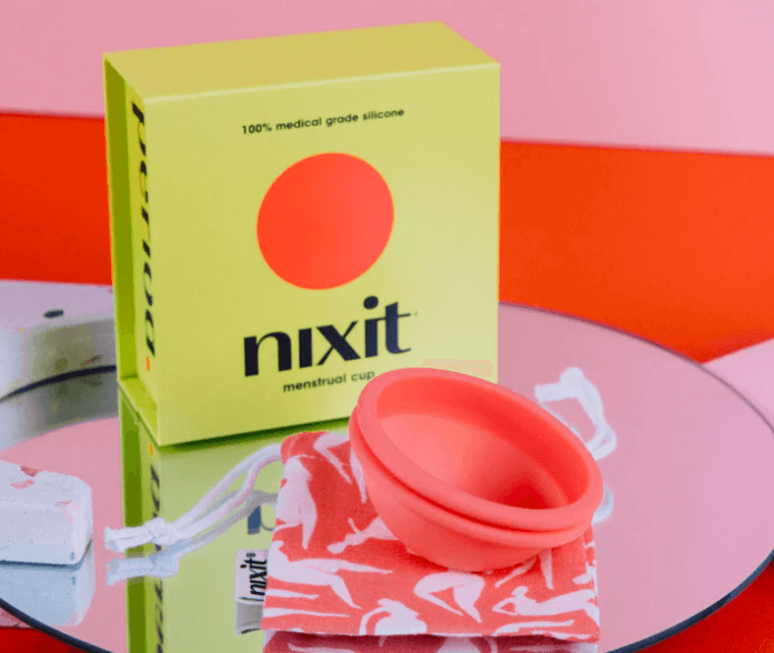 a pink menstrual disc on a carry bag in front of a green product box