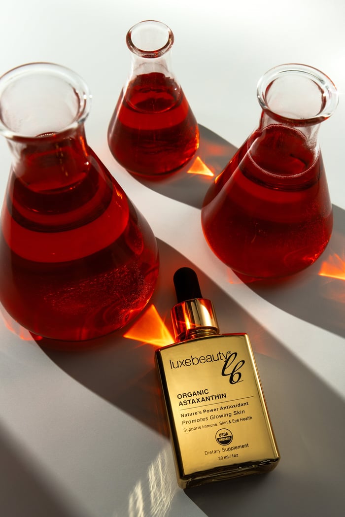 Best astaxanthin supplement by Luxe Beauty shown with laboratory glass beakers highlighting certified organic purity and antioxidant potency
