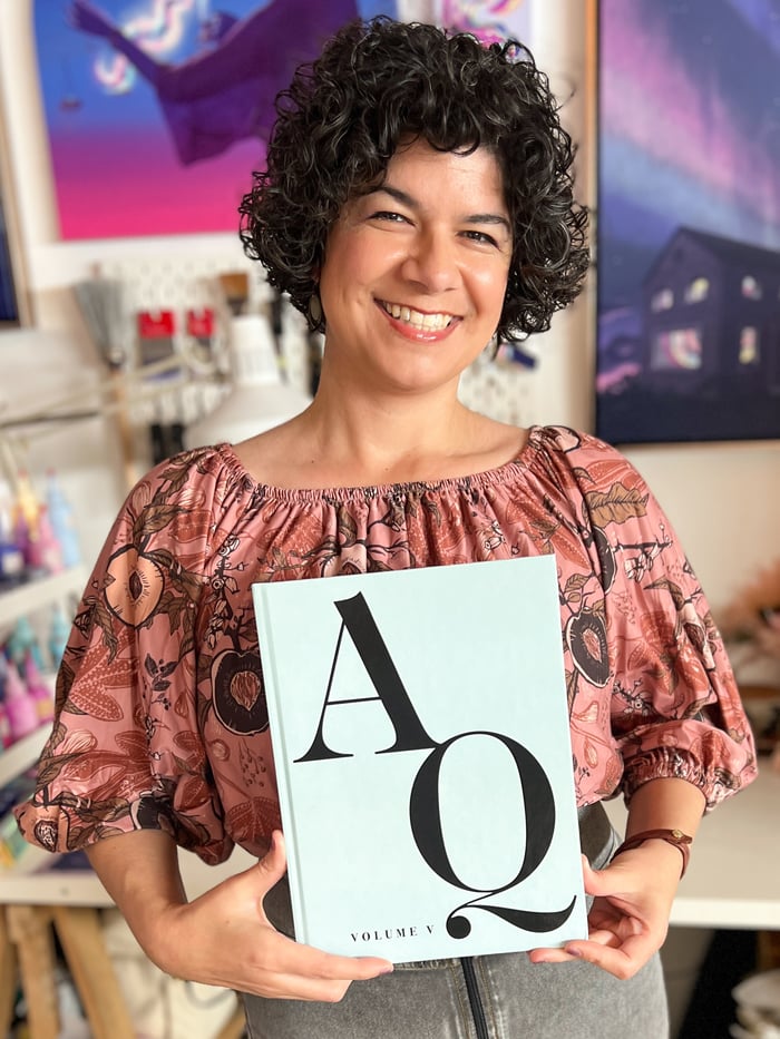 Teri Hendrich C., holding a copy of Art Queens, Volume V.
