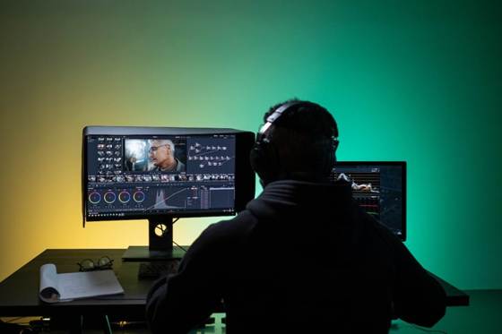 Video editor working through footage at a monitor, showing the manual effort behind video redaction