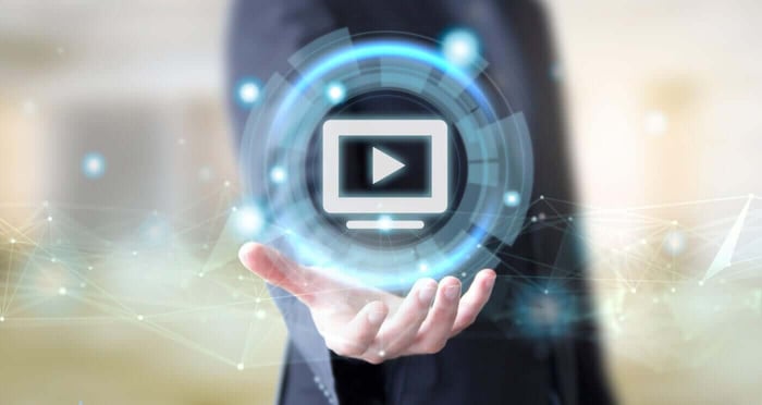 Hand holding a glowing video play icon, representing advanced technology used in video redaction services