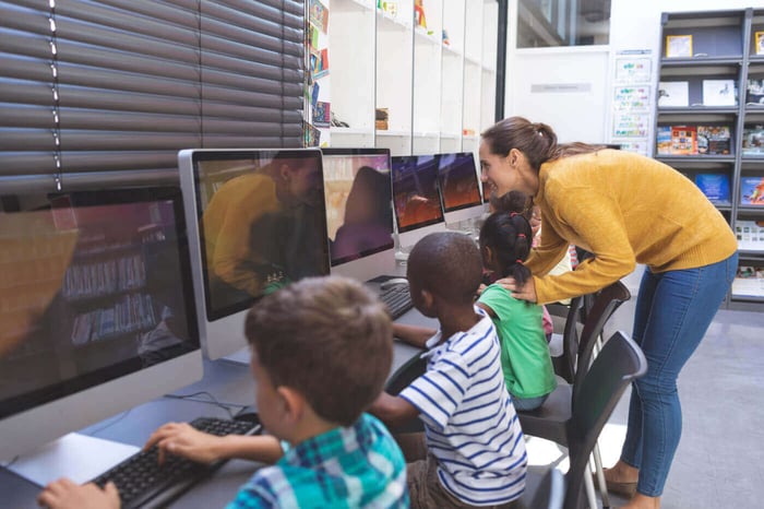 Teacher assisting students at classroom computers, representing student privacy in school video records