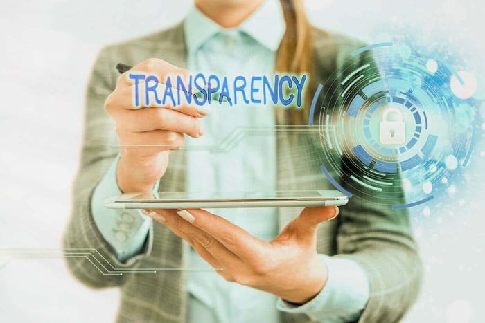 Person writing the word Transparency beside a padlock icon, representing accountable redaction practices