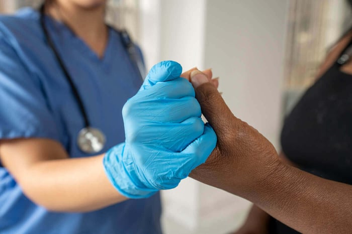 Clinician in a medical glove holding a patient's hand, representing protected health information in video records