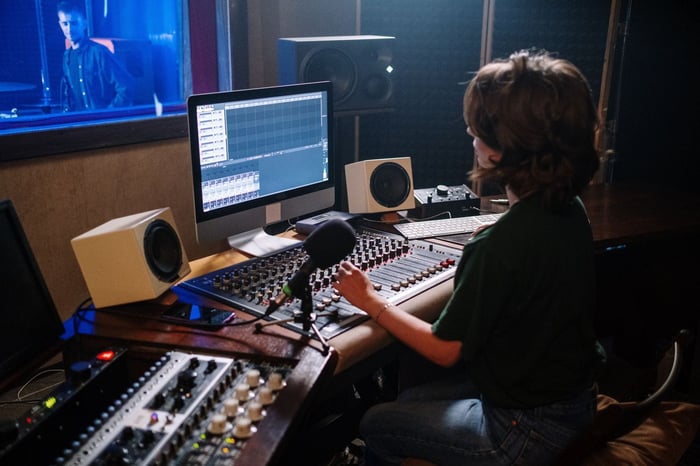 Audio engineer seated at a workstation in a treated studio reviewing a recording for forensic audio enhancement