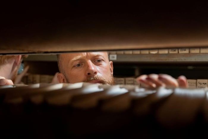 Records staff member searching through a long shelf of stored files, representing the intake and deadline tracking work Colorado body camera records law requires of records units