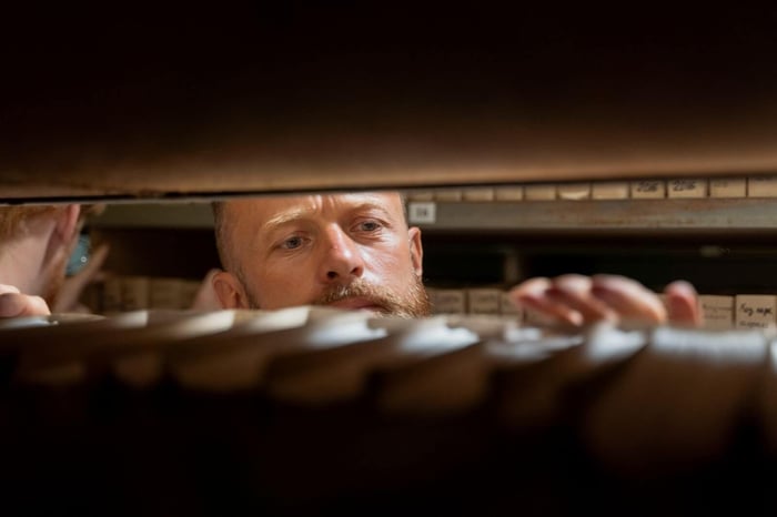 Records staff member searching through a long shelf of stored files, representing the intake and deadline tracking work Colorado body camera records law requires of records units