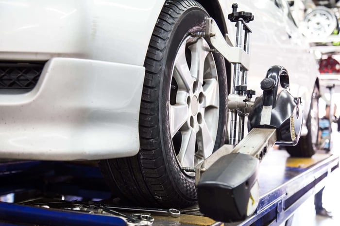 Gros plan du pneu serré avec aligneur subissant l'alignement automatique des roues dans le garage