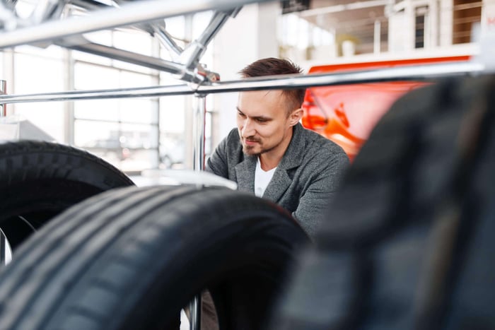 L' homme choisit des pneus pour une nouvelle voiture dans la salle d'exposition