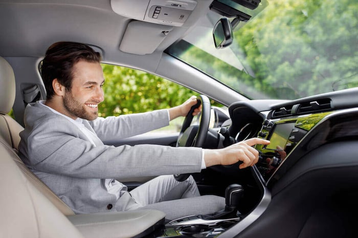 Homme comfortable au volant de sa voiture en expérimentant la technologie sur l'écran de bord