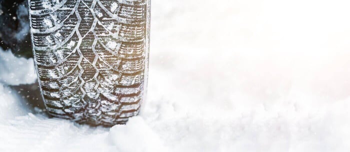 Un pneu clouté et enneigé sur une terre hivernale