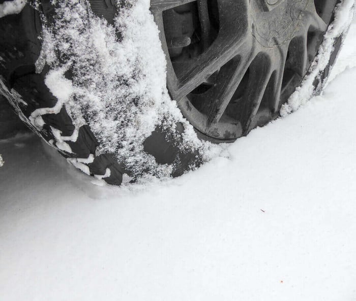 Gros plan d'un pneu tout-terrain compactant la neige devant lui