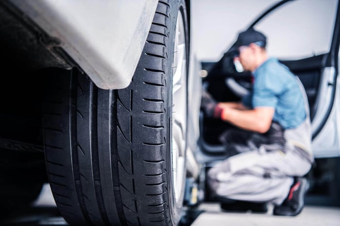 Pneu arrière avec vue floue d'un mécanicien effectuant le service de voiture de garantie planifiée
