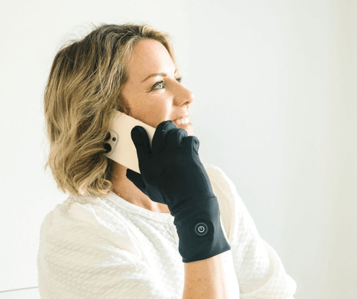 Woman wearing thin heated gloves for arthritis and talking on the phone
