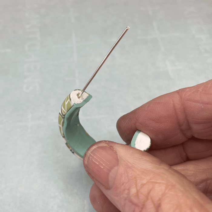 Dry-fitting the looped wire in the polymer clay hoop earring drilled hole.