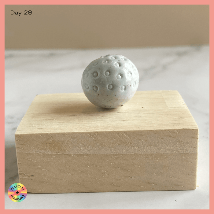 Pale green polymer clay bead with circular indentations.