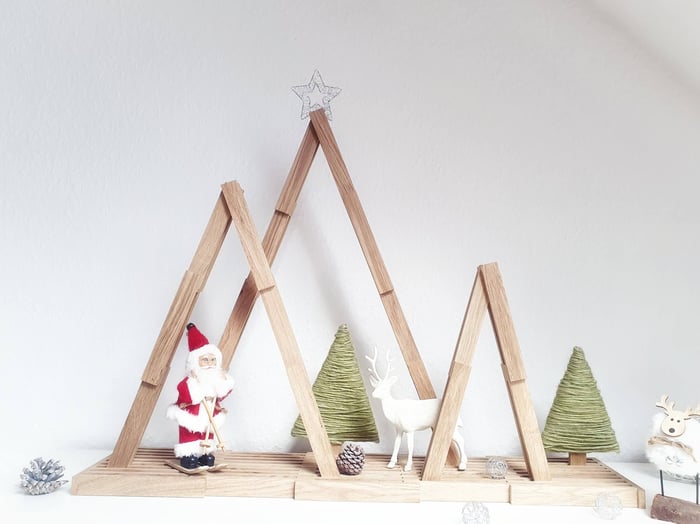 Ein dekorativer Tannenwald aus Easy-Sticks auf einer Holzplatte, weihnachtlich arrangiert