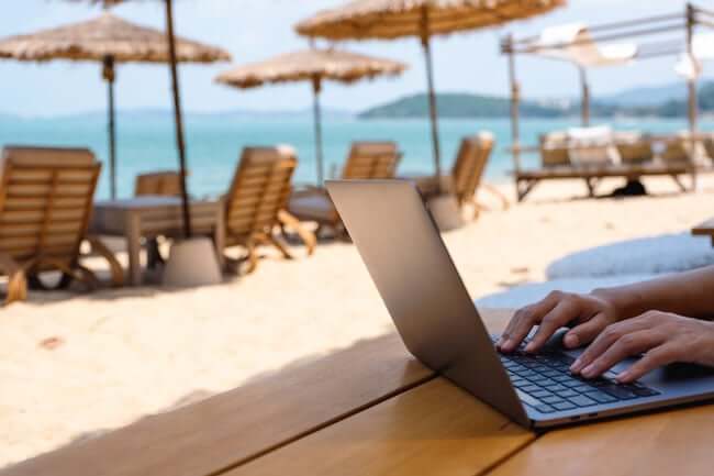 Photo of a digital nomad working on a laptop at the beach on the Costa del Sol