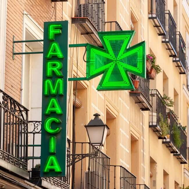 Photo of a pharmacy sign down a street of a town on the Costa del Sol