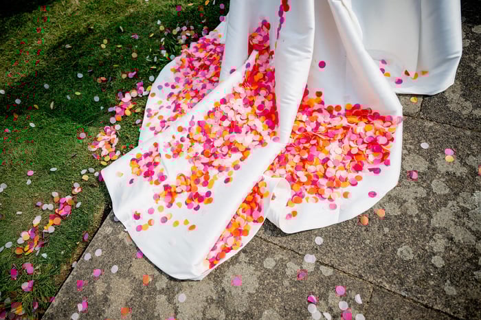 A train of a white wedding dress full of wedding confetti circles in shades of pink and orange