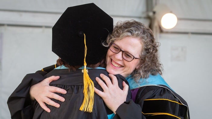 Dr. Susan Iverson hugging a student at commencement