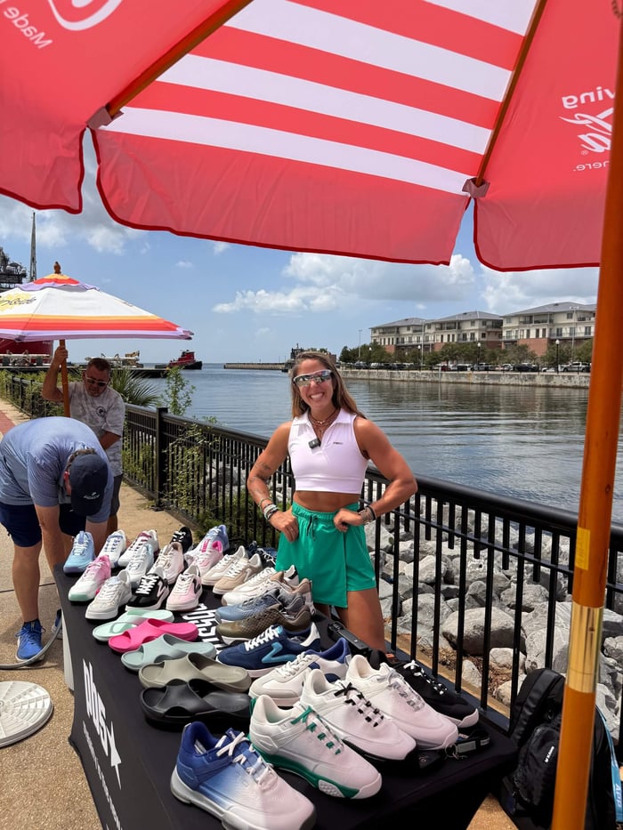Alex in front of a table of PB5star shoes, set up by the water at Portside Pickle in Pensacola.