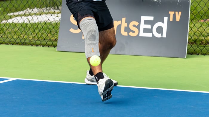 Close up shot of a pickleball mid air and a player behind it