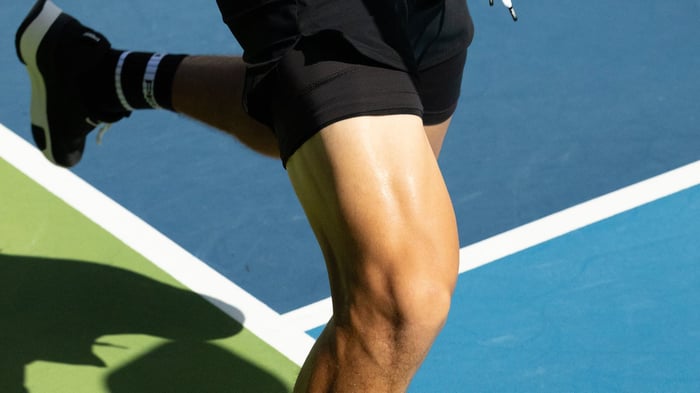 Close up shot of a man's thigh and foot running on a pickleball court