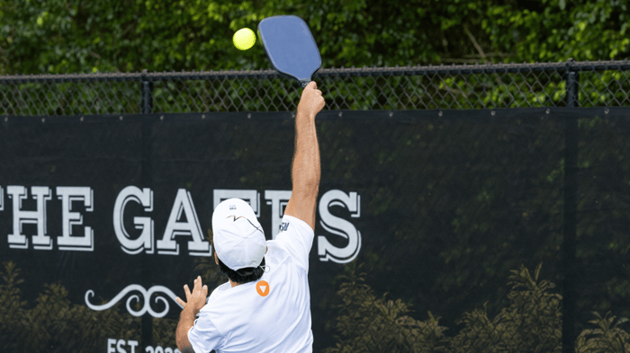 Player jumping to hit a pickleball