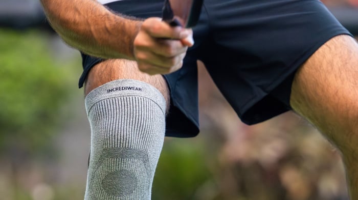 Close up shot of man's knee and hand holding a paddle