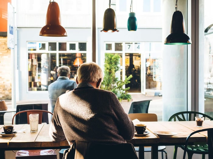 older man in cafe looking out a window
