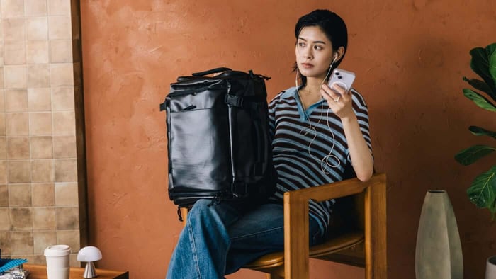 手提黑色 Bagsmart 38L 後背包的休閒穿搭展示，呈現挺拔外觀與中性美學，符合日常與出差的高質感【後背包推薦】。