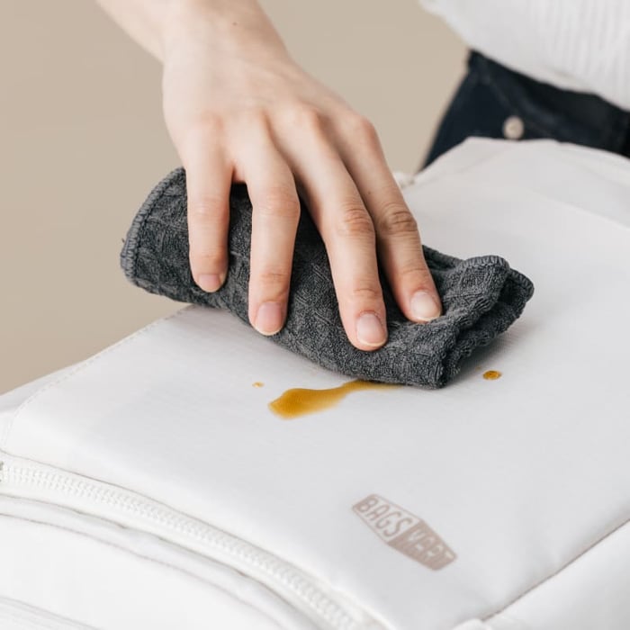 使用濕布輕鬆擦拭 Bagsmart 後背包表面的咖啡髒污,展示高階 TPU 覆膜防潑水、耐磨抗撕裂且髒污不易附著的特性,讓後背包清潔保養更省心。