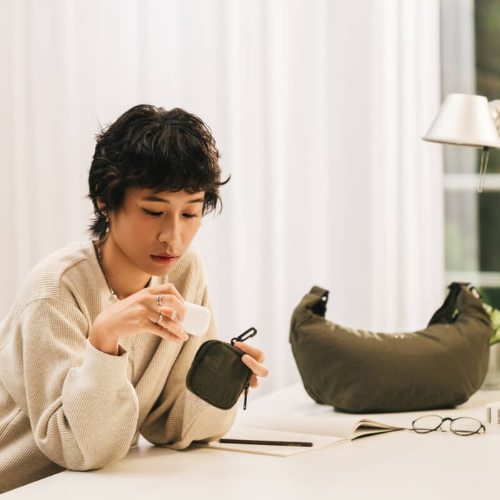 在室內展示「日常輕旅防盜斜肩包」隨附的軍綠色小收納包,可用於分類存放藍牙耳機、零錢等重要小物件。