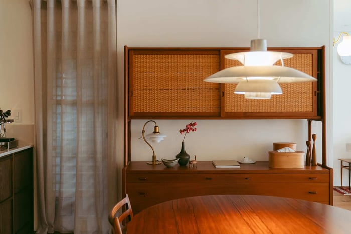 餐廳區的復古柚木餐櫃與藤編櫃門,上方裝飾著 Louis Poulsen PH 系列經典燈具,呈現洗鍊風格