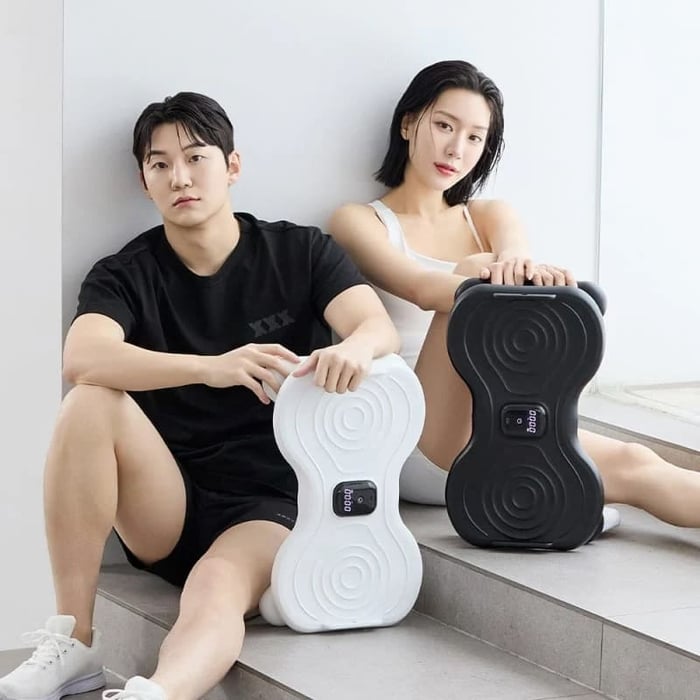 穿著極簡運動服的男女坐在階梯上,手持小蠻腰懶人扭扭板。這款器材結合了有氧與動態核心訓練,為現代久坐族解答了核心運動有哪些更無痛有趣的鍛鍊方案。